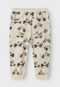 Beige Baumwoll-Jogginghosen mit einem verspielten Druck von Fahrzeugen, darunter Lastwagen und Motorräder, zeichnen sich durch eine weiche Textur und einen gerippten Bund aus.