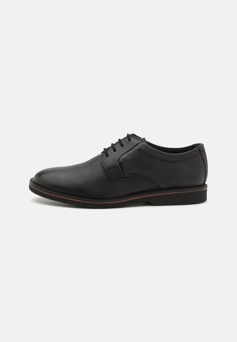 Chaussure formelle en cuir noir pour homme avec lacets, talon bas et bordure subtile marron sur la semelle, vue de côté gauche sur fond blanc.