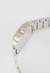 Silver stainless steel watch with a square case, textured push crown, and a polished link bracelet. Smooth surface with engraved details.