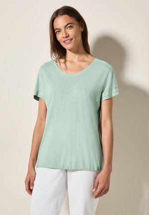 T-shirt vert clair à manches courtes avec un col en V, fabriqué en tissu doux et texturé. Présente des boutons sur l'épaule pour un détail élégant.