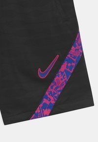Tessuto nero con strisce astratte a motivo in rosa e blu e un logo swoosh Nike blu contornato di rosa ricamato vicino all'orlo.