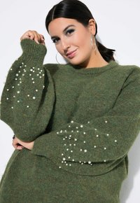 Maglione verde lavorato a maglia con tessuto testurizzato e maniche a sbuffo decorate con dettagli di perle sparse. Collo rotondo e vestibilità rilassata.