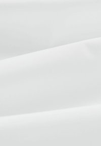 Weißer Stoff mit glatter Textur, der gefaltete Lagen zeigt, die sanfte, fließende Linien und subtile Schatten erzeugen.