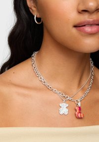 Collana a catena con maglie in metallo argentato, con ciondolo a forma di orsetto argento e un charm a forma di orso rosa e arancione.