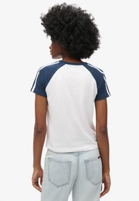 Hvid og marineblå kortærmet raglan t-shirt med rund hals; blød tekstur; marineblå ærmer med tynde hvide striber.
