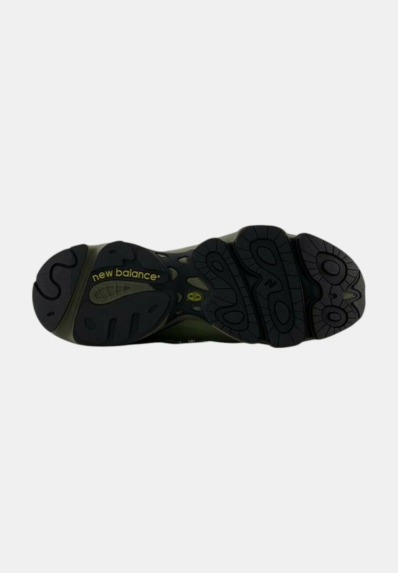 Semelle en caoutchouc noir avec des motifs de semelle prononcés, arborant le logo New Balance en jaune. La tige présente des détails texturés en vert foncé.
