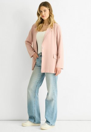 Pink blazer with a relaxed fit, single-button closure, and pocket; paired with light wash flared jeans and white sneakers.