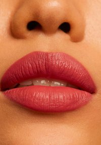 Matte läppfärg i mjuk rosaskugga applicerad på väldefinierade läppar, med en jämn textur och synliga fina linjer för ett naturligt utseende.