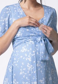 Modrá květinová zavinovací šaty s krátkými rukávy, v-výstřihem, se zavazováním v pase a knoflíky na přední straně, vyrobené z lehkého materiálu.