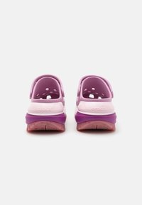 Purple and pink Crocs with a closed toe design, rear straps, and ventilation holes; textured outsole for grip and flexibility.