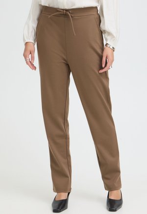 Pantaloni marroni a gamba dritta con vita con coulisse, indossati con una camicetta bianca e scarpe nere con punta su un modello in piedi.