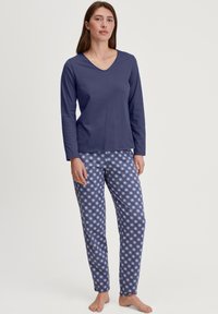 Marineblauwe longsleeve top met een V-hals, gecombineerd met lichtblauwe pyjamabroek met een patroon van kleine witte bloemen.