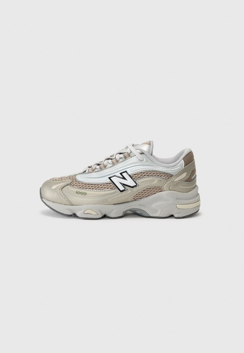 Baskets New Balance 1100 beige et blanches avec détails en mesh et cuir, fermeture à lacets et semelle épaisse en caoutchouc, vues de côté.
