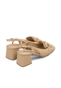 Sandali con tacco beige, con punta appuntita, dettagli con cinturino, accenti dorati e un tacco a blocco spesso. Realizzati in materiale sintetico liscio.