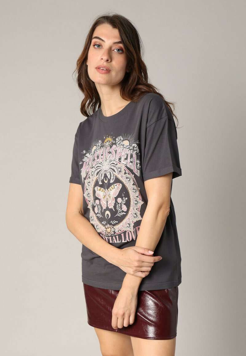 Camiseta gráfica gris con un diseño de mariposa y acentos florales en rosa y crema. Combinada con una falda de cuero brillante burdeos.