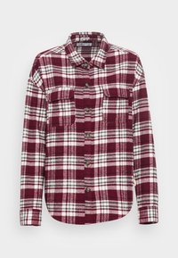 Rutig flanellskjorta i röd och vit med två bröstfickor, knäppning fram och långa ärmar. Tillverkad av strukturerat material.