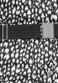 Γούνινο μπουφάν με ασπρόμαυρο ζωικό μοτίβο, διαθέτει υφασμένη μαύρη μέση και ασημί μεταλλική αγκράφα.