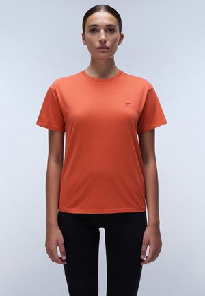 Orange cotton t-shirt with short sleeves, round neckline, and a small logo detail on the chest, paired with black fitted pants.