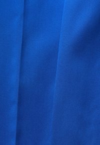 Tissu bleu avec de légers plis verticaux et une texture fine en tissage diagonal visible sur toute la surface.