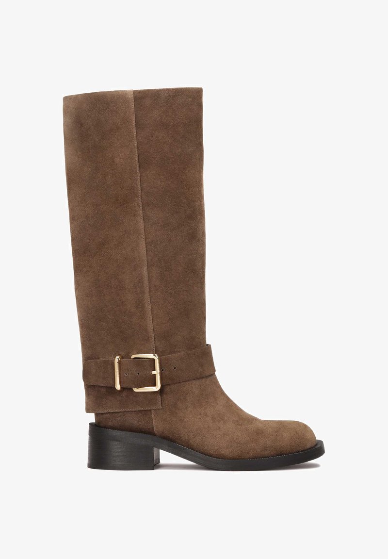 Barna velúrbőr térdmagasságú csizma lekerekített orral, széles pánttal és arany csattal díszítve. Keskeny sarok, textúrált fekete talppal.