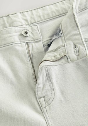 Pantaloni din denim gri deschis, cu închidere cu fermoar, buton metalic și detalii subtile de cusătură.Țesătura are o textură netedă.