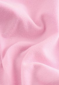 Różowa bawełniana tkanina o miękkiej teksturze, charakteryzująca się gładką, lekko teksturowaną powierzchnią i delikatnym układaniem.