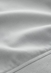 Close-up of soft, light gray fabric with subtle texture and smooth, curved folds.