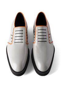 Grijze leren schoenen met zwarte accenten, voorzien van verticale groeven, oranje bies en een gladde, glanzende afwerking. De zool is gestructureerd.