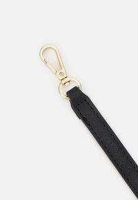 Une sangle noire en matériau texturé avec un fermoir en métal doré. Dotée d'un anneau rond pour attache et d'une finition lisse et élégante.