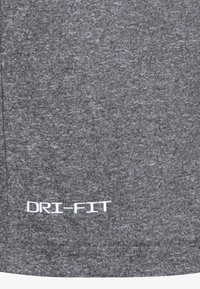 Grå DRI-FIT plagg med teksturert stoff og en subtil heather-mønster. Logoen er trykket i hvitt nær bunnen.