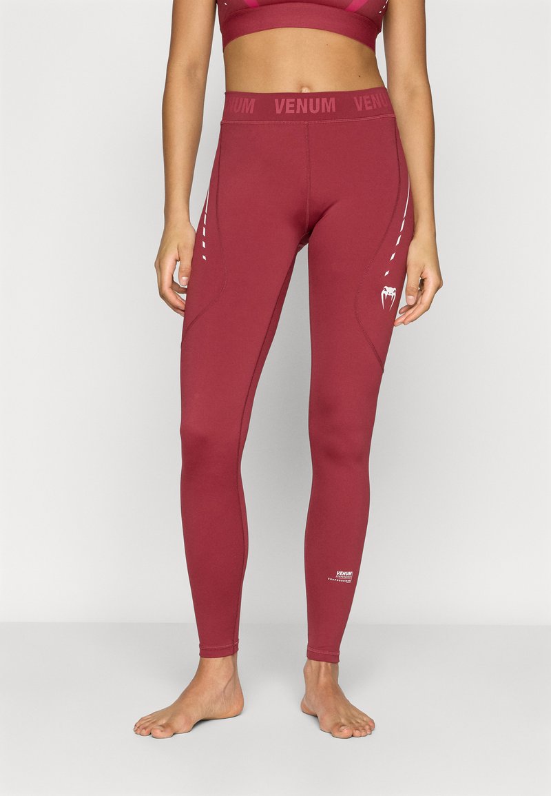 Leggings atléticas cor de vinho feitos de tecido elástico com um design ajustado. Apresentam a marca VENUM e pequenos detalhes de destaque nas laterais.