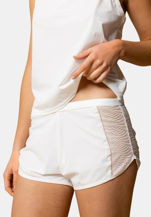Shorts de sport blancs avec des panneaux latéraux texturés et un design en tissu lisse. La taille est élastique et ajustée pour le confort.