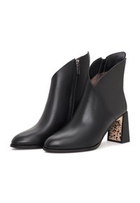 Paire de bottines en cuir noir avec fermeture éclair latérale et talons blocs présentant un motif beige et noir tacheté.