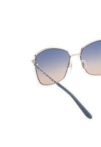 Ochelari de soare cu un design geometric, supradimensionat; lentilele cu gradient trec de la albastru la maro deschis; cadru metalic de aur; accente texturate albastre pe brațe.