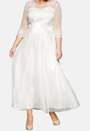 Robe blanche avec un corsage ajusté et des manches trois-quarts transparentes brodées. Jupe fluide et délicates touches de dentelle florale partout.