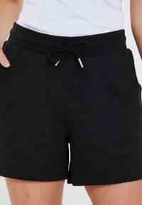 Pantaloni corti neri realizzati in un tessuto morbido con cintura elastica, cordoncino regolabile e due tasche frontali. Presentano dettagli di cucitura discreti.