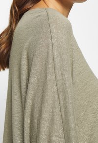 Grüner Stricktop mit lockerer Passform, weichem Material und drapierten Ärmeln, mit einem dezenten Glanz und leichtem Stoff.