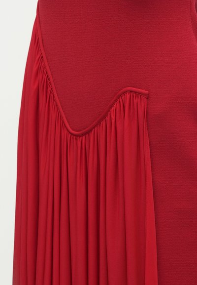 Czerwona sukienka z marszczoną fakturą z tyłu, gładkim górnym partiem i zaokrąglonym dekoltem. Miękki materiał o zwiewnym kroju.