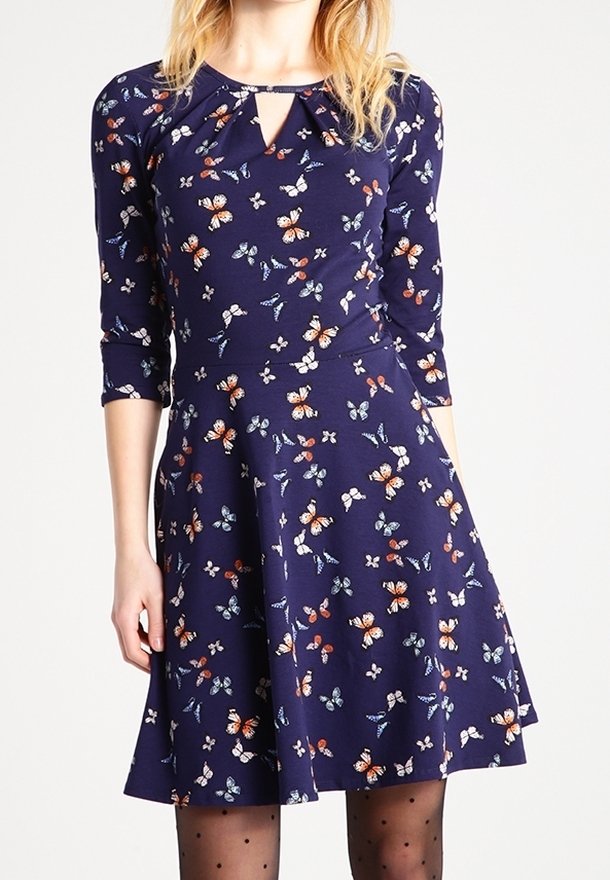 Marinblå klänning med blommig fjärilstryck, trekvartsärmar, en nyckelhålsutskärning och en utsvängd kjol. Tillverkad av mjukt, elastiskt tyg.