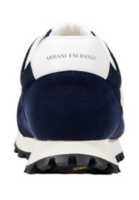 Zapatilla deportiva azul marino con panel trasero blanco, texturas de malla y ante, suela de goma negra y logotipo en relieve "Armani Exchange".