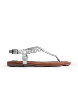 Sandal plana de tiras metálicas plateadas con un upper texturizado y una plantilla de ante marrón, que presenta una correa con hebilla para un ajuste seguro.