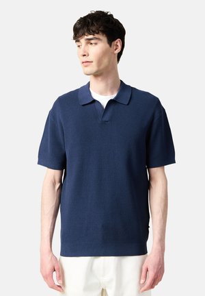 Camisa de polo de manga corta en azul marino con un tejido texturizado, que cuenta con un collar clásico y una sutil abertura en forma de V en el escote.