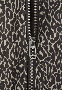 Cerniera metallica su tessuto con stampa leopardata nera e beige, cursore della cerniera centrato con incisione "STREET ONE".