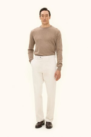 Beige neule, kerma housut, ruskeat kengät. Yksinkertainen muotoilu, napakka siluetti, pehmeä rakenne ja nappidetaili housuissa.