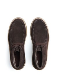 Bottines en suède marron avec un bout arrondi, un laçage, des coutures blanches contrastantes et une semelle en caoutchouc.