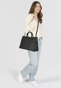 Bolso de mano de cuero negro con dos asas superiores y una correa de hombro desmontable, con una textura lisa y una forma estructurada.