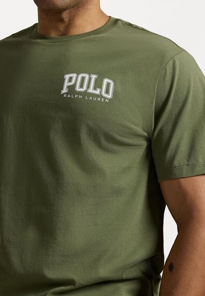 Alyvuogieji medvilniniai marškiniai su apvali kaklo išpjova ir trumpomis rankovėmis. "POLO RALPH LAUREN" logotipas išsiuvinėtas baltu siūlu kairėje krūtinės pusėje.