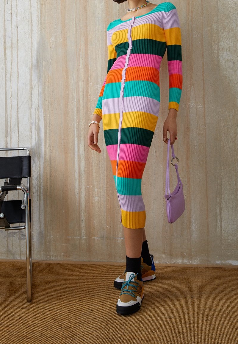 Vestido de punto acanalado colorido con mangas largas, con rayas alternas en rosa, verde, amarillo y azul, que presenta un cierre de botones en la parte delantera.