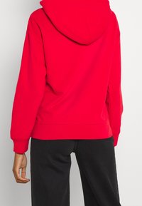 Sudadera roja con capucha, de mangas largas, puños y dobladillo acanalados, hecha de una tela suave. Cuenta con una gran capucha y un ajuste holgado.