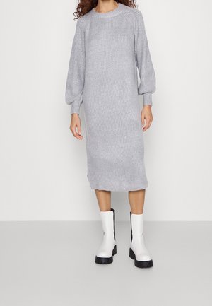 Graues Strickkleid mit gerippter Textur, langen Puffärmeln und Rundhalsausschnitt, kombiniert mit weißen Stiefeletten mit schwarzer Sohle.